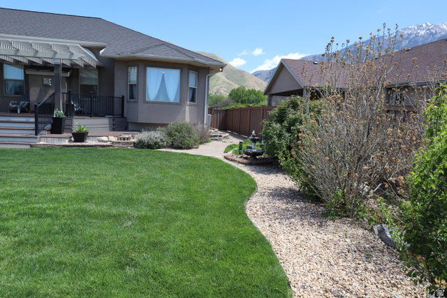 1055 North 1000 East Mapleton, UT 84664 - Photo 85 of 112 Expansive backyard featuring a manicured lawn, a gravel pathway, and a two-tier deck with a pergola