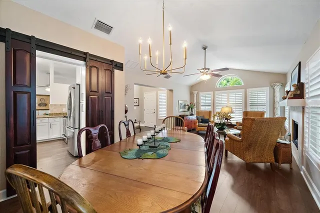 a very nice looking dining room with kitchen island furniture a chandelier a large window and kitchen view