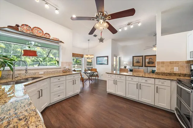 a large kitchen with stainless steel appliances a stove a sink dishwasher and a oven with white cabinets