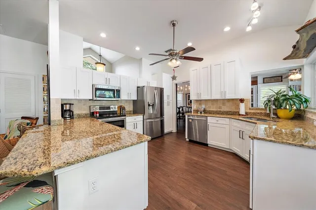 a large kitchen with granite countertop a large counter top space a sink stainless steel appliances and cabinets