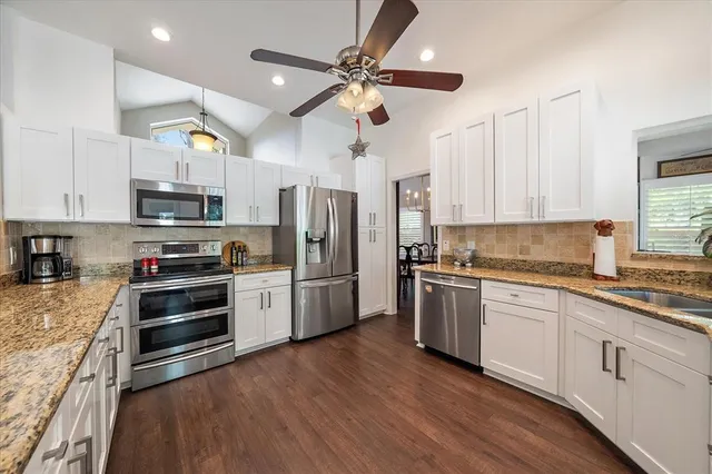 a kitchen with stainless steel appliances a stove a refrigerator and white cabinets