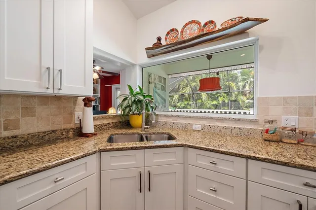 a kitchen with granite countertop a sink and a white cabinets