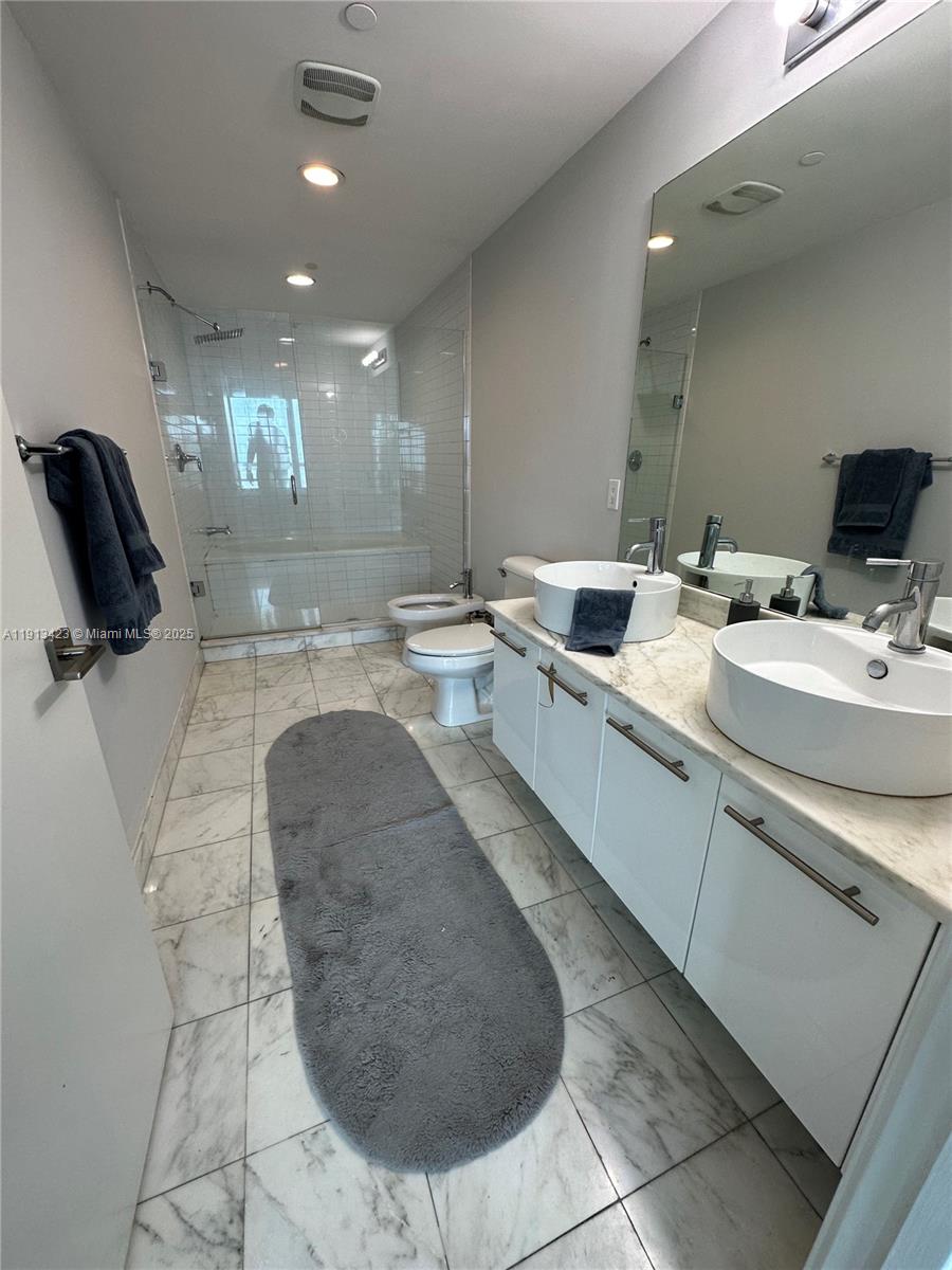 888 Biscayne Boulevard, Unit 4302 Miami, FL 33132 - Photo 3 of 6 a bathroom with a sink a toilet and mirror