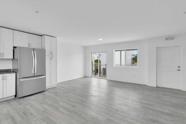 a kitchen with stainless steel appliances granite countertop a refrigerator a stove and white cabinets with wooden floor