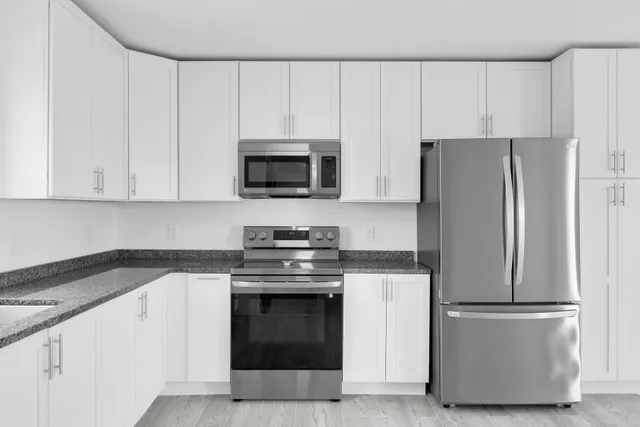 a kitchen with granite countertop white cabinets and stainless steel appliances