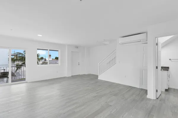 a view of an empty room with window and wooden floor