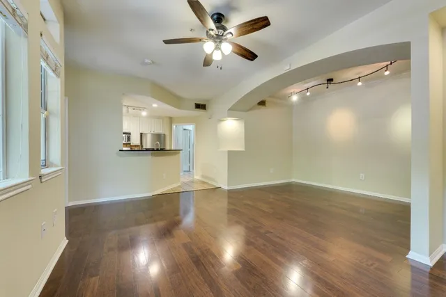 an empty room with wooden floor and a ceiling fan