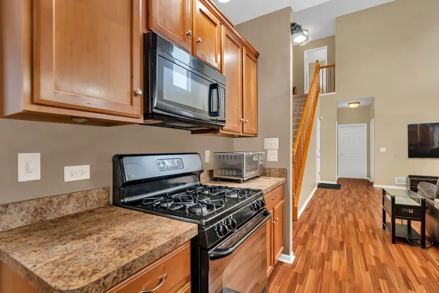 a living room with stainless steel appliances kitchen island granite countertop furniture and a wooden floor