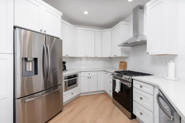a kitchen with stainless steel appliances white cabinets and a refrigerator
