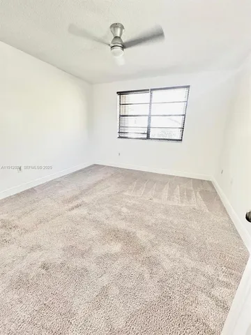 an empty room with windows and ceiling fan