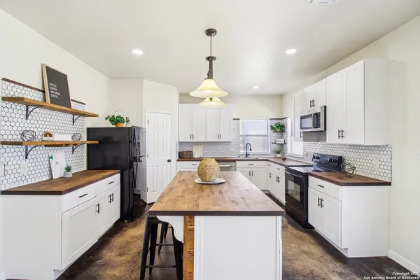 a kitchen with stainless steel appliances granite countertop a refrigerator a sink dishwasher a stove a dining table and chairs with wooden floor