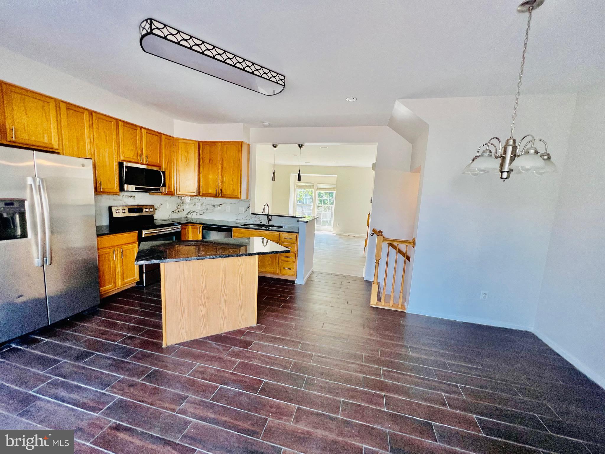 13251 Revillo Loop Woodbridge, VA 22191 - Photo 9 of 32 a kitchen with stainless steel appliances a refrigerator a stove a sink dishwasher and a dining table with wooden floor
