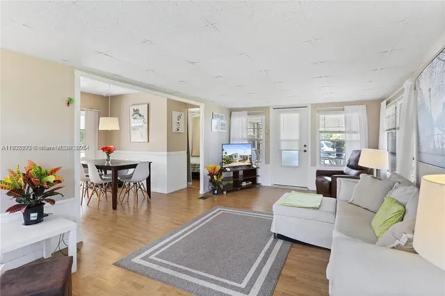 a living room with furniture and a dining table with wooden floor