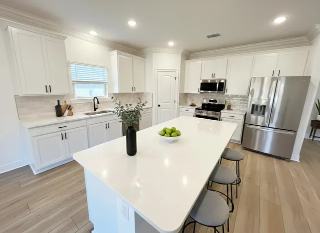 a kitchen with a sink a refrigerator and white cabinets