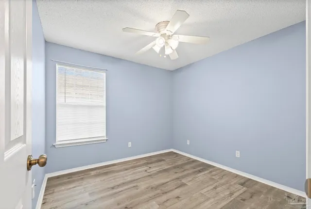 an empty room with a window and a fan