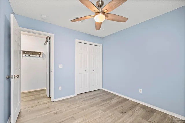 a view of empty room with wooden floor and fan
