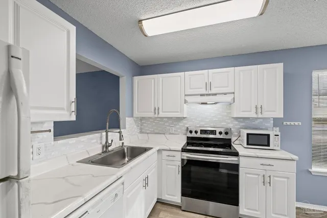 a kitchen with granite countertop a stove sink and dishwasher