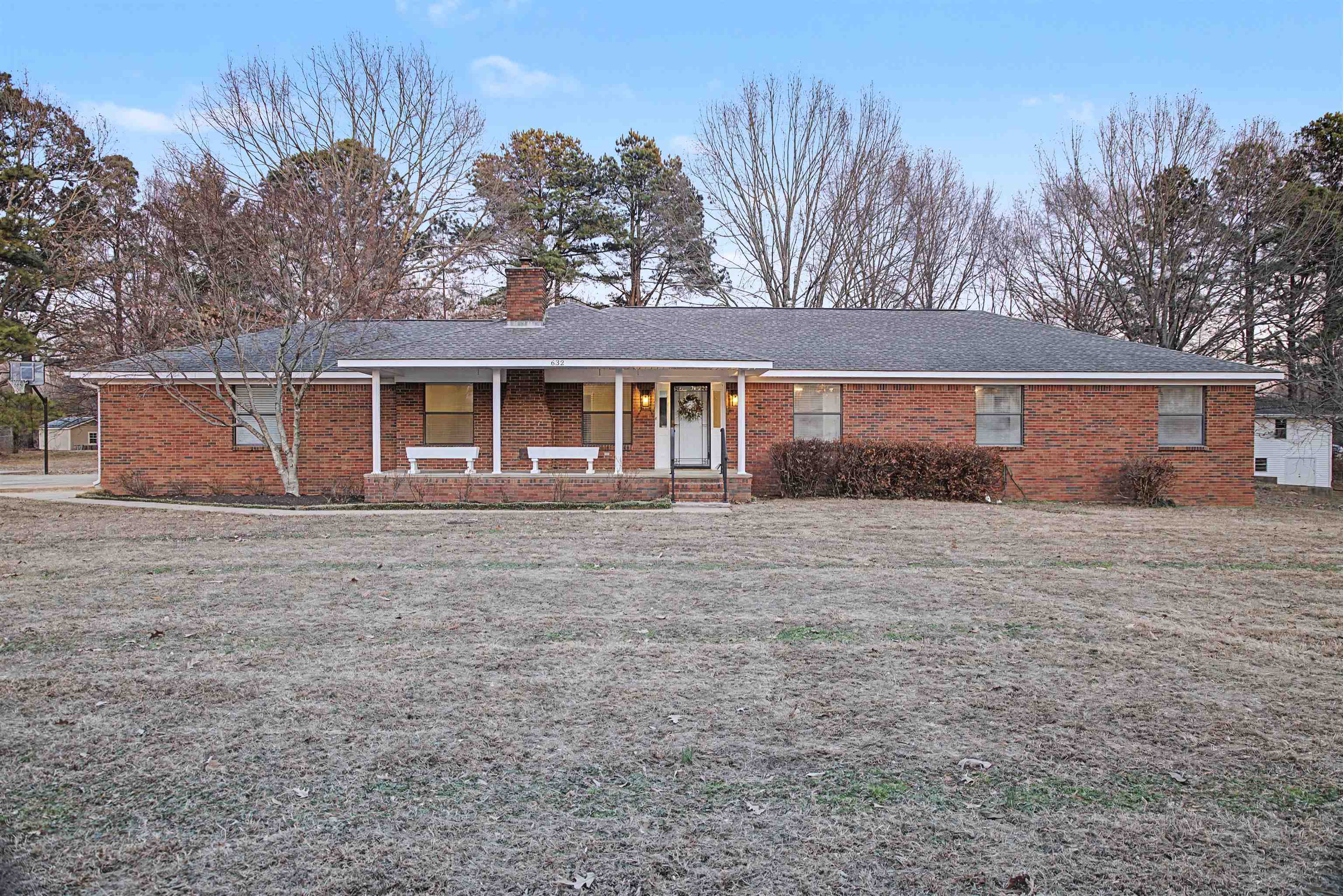 Ranch-style house with a porch, brick siding, a chimney, and a shingled roof