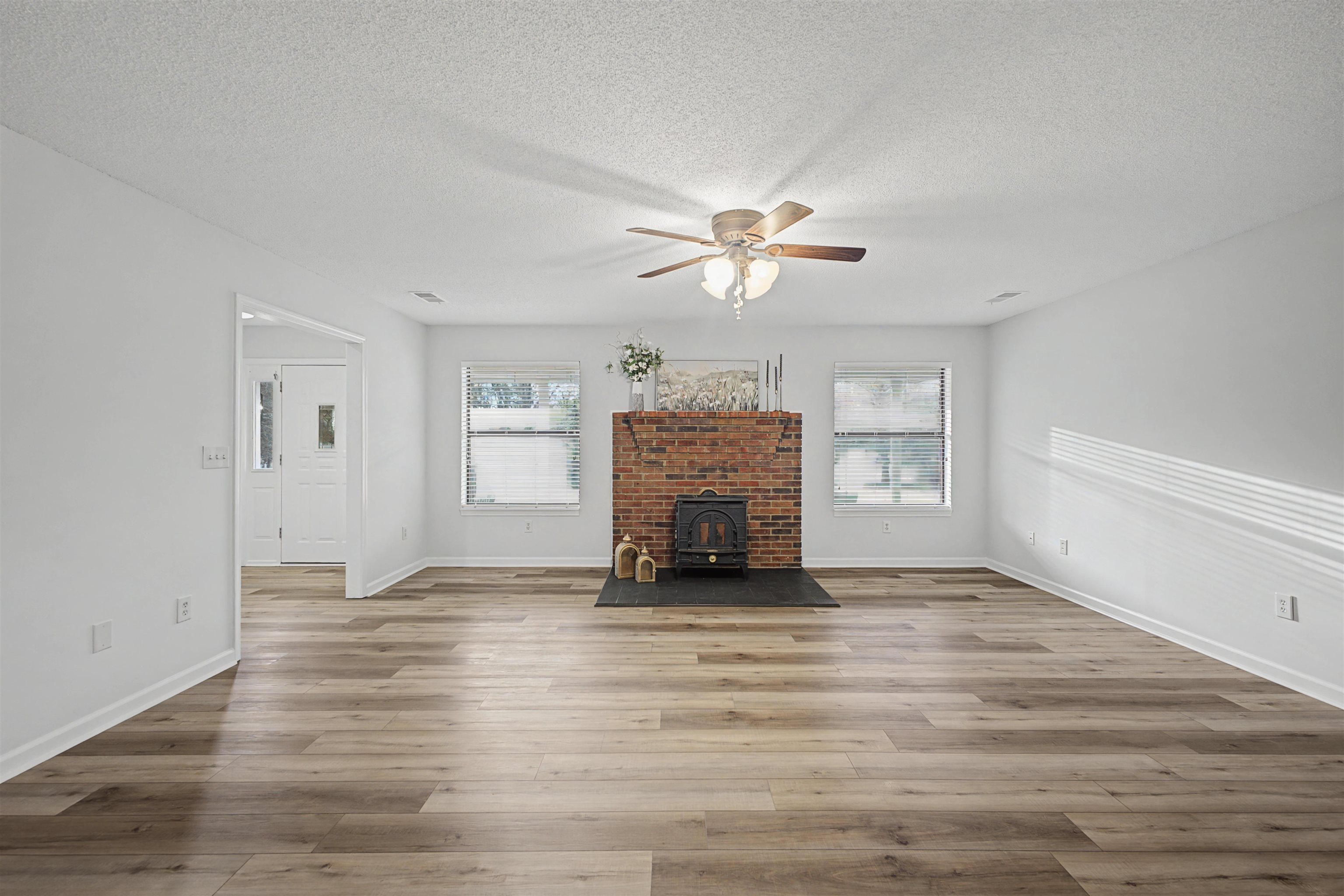 632 Cullum Road Munford, TN 38058 - Photo 13 of 38 Unfurnished living room featuring ceiling fan, a wood stove, light wood-style flooring, and a textured ceiling