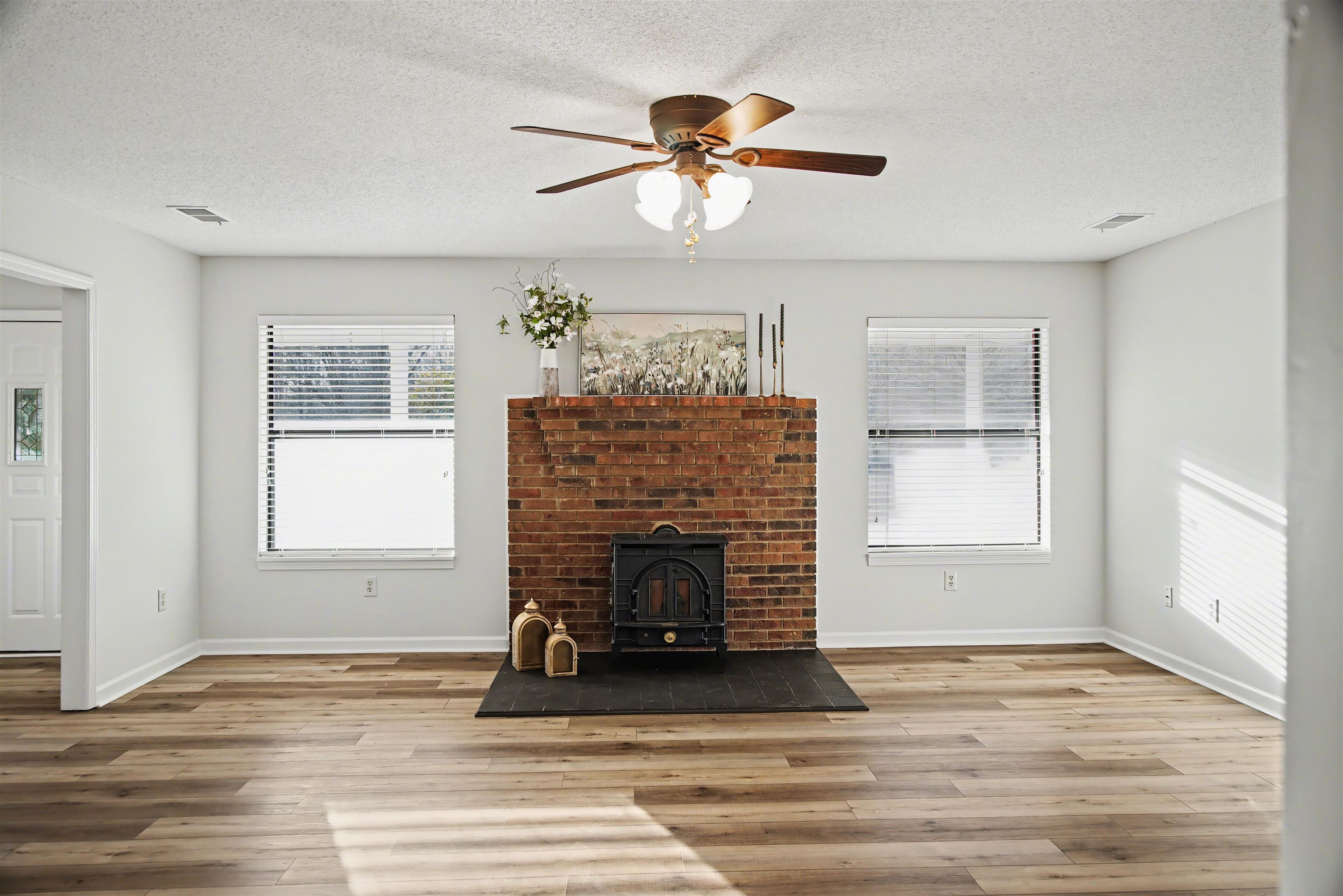 632 Cullum Road Munford, TN 38058 - Photo 14 of 38 Living room featuring a ceiling fan, a textured ceiling, light wood-style floors, and a wood stove
