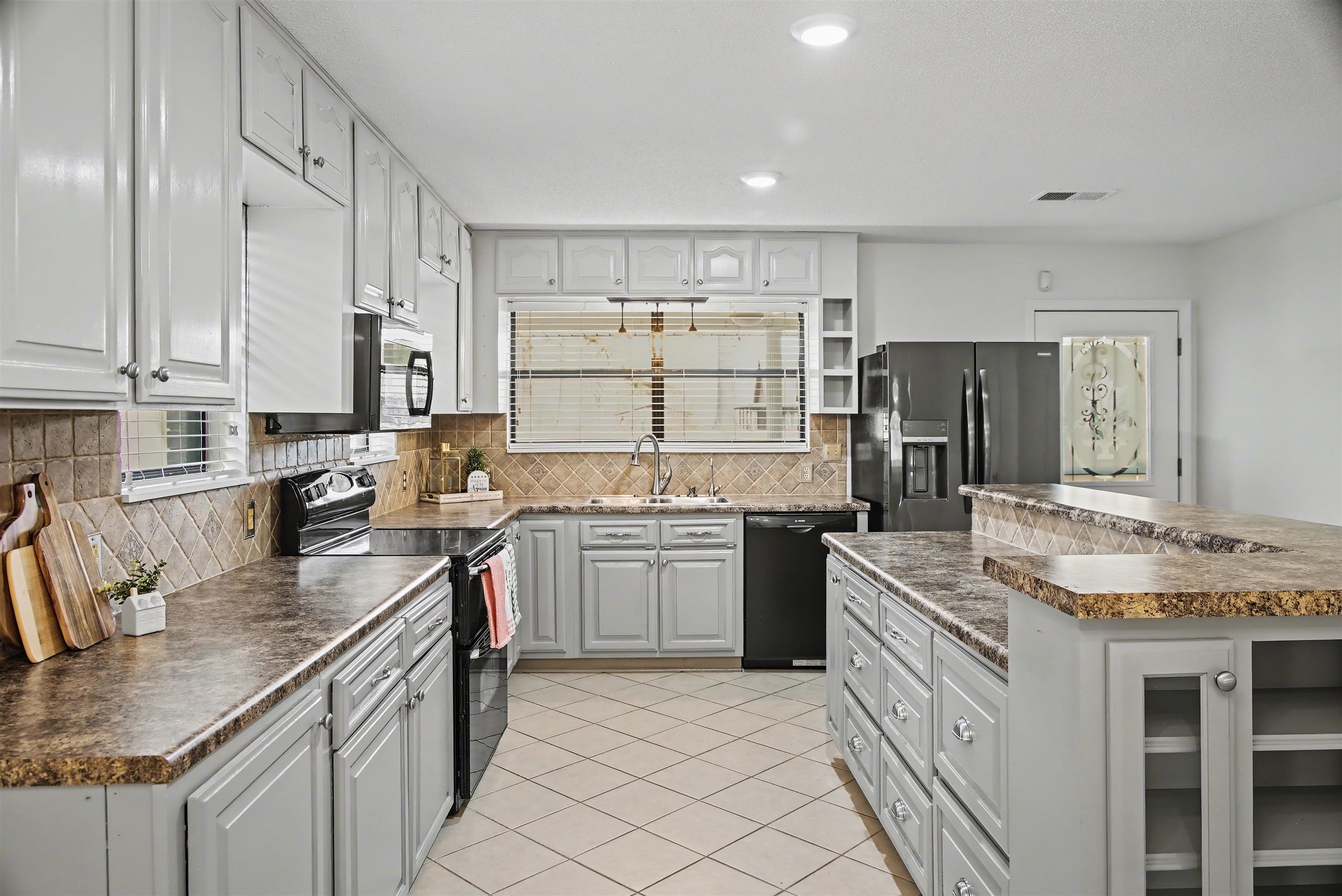 632 Cullum Road Munford, TN 38058 - Photo 8 of 38 Kitchen with black appliances, dark countertops, light tile patterned floors, white cabinets, and tasteful backsplash