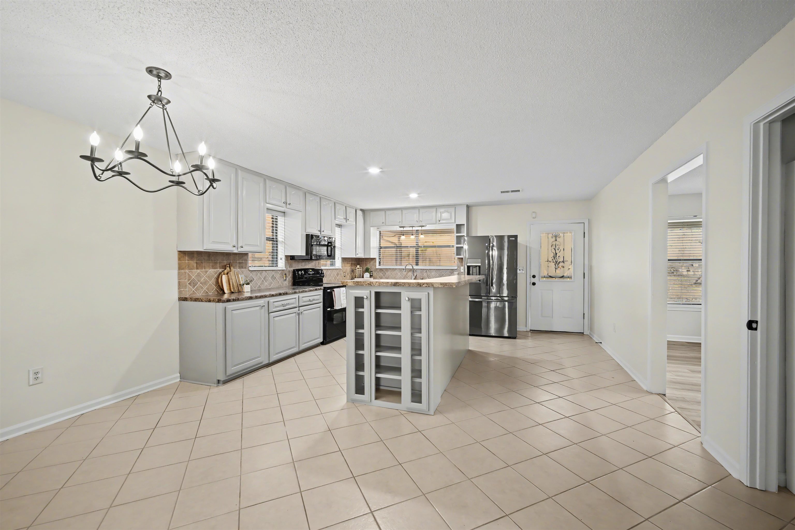 632 Cullum Road Munford, TN 38058 - Photo 10 of 38 Kitchen featuring black appliances, decorative backsplash, a center island, light tile patterned flooring, and white cabinets