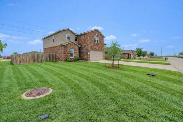 a view of a big house with a big yard and a large tree
