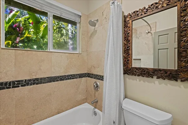 a bathroom with a shower a toilet and a window
