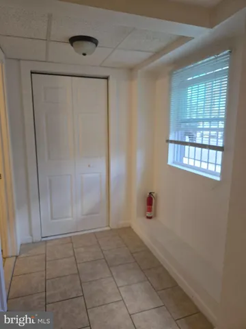 a view of an empty room with window and chandelier fan