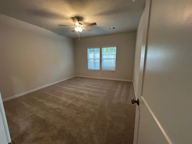a view of an empty room with a chandelier fan