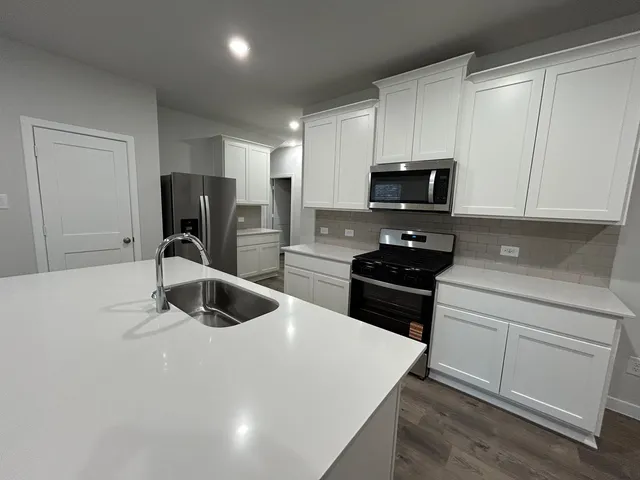 a kitchen with a sink a refrigerator and cabinets