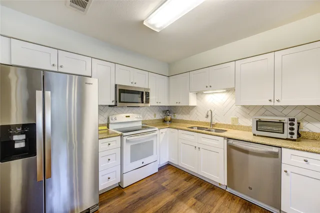 a kitchen with stainless steel appliances a sink cabinets and a refrigerator