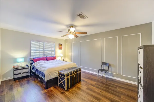 a bedroom with a bed a table and wooden floor