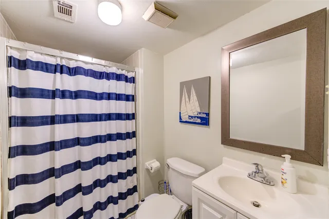a bathroom with a sink a toilet a mirror and shower curtain