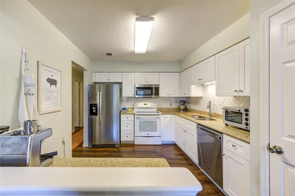 a kitchen with stainless steel appliances granite countertop a refrigerator sink and stove
