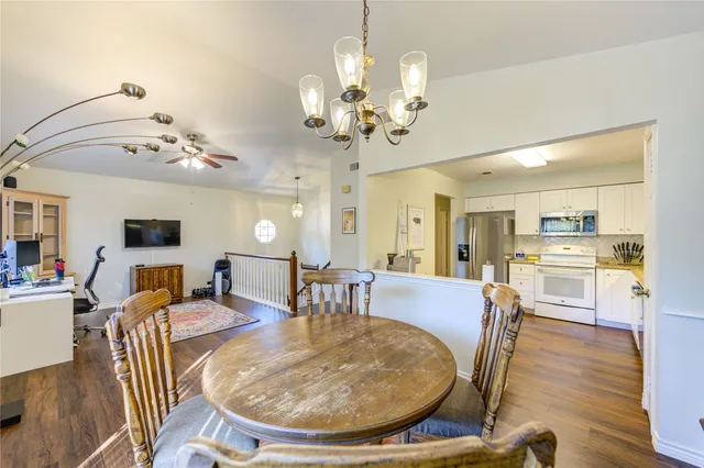 a dining room with wooden floor a chandelier a wooden table and chairs