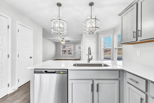 a kitchen with stainless steel appliances granite countertop a sink and a chandelier