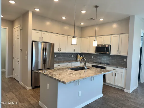 a kitchen with stainless steel appliances granite countertop a sink a refrigerator a stove and a refrigerator with wooden floor
