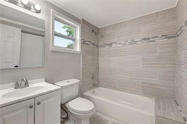 a bathroom with a granite countertop toilet a sink and bathtub