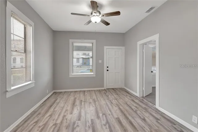 a view of empty room with wooden floor and fan