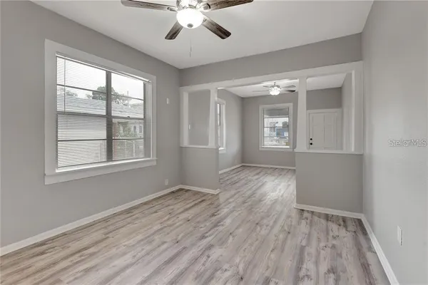 a view of an empty room with a window and wooden floor