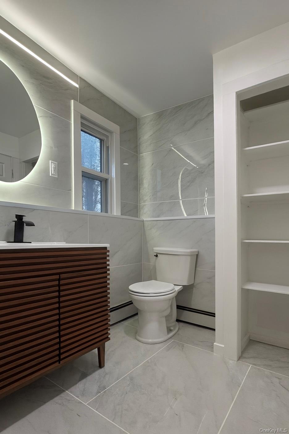 88 Cold Spring Road Liberty, NY 12754 - Photo 14 of 32 Main level bathroom with tile walls, marble finish floors, a baseboard radiator, and vanity