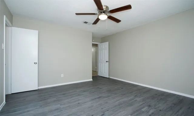 an empty room with wooden floor and ceiling fan
