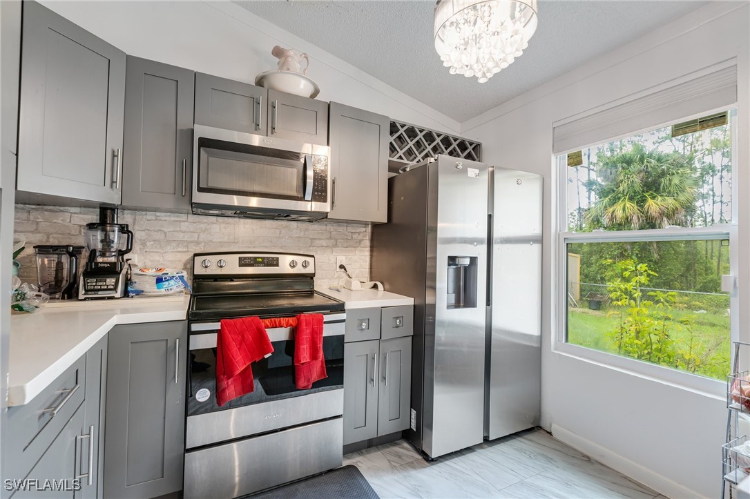 503 East 13th Street Lehigh Acres, FL 33972 - Photo 5 of 15 a kitchen with stainless steel appliances granite countertop a refrigerator a stove top oven a sink and dishwasher a refrigerator with wooden floor
