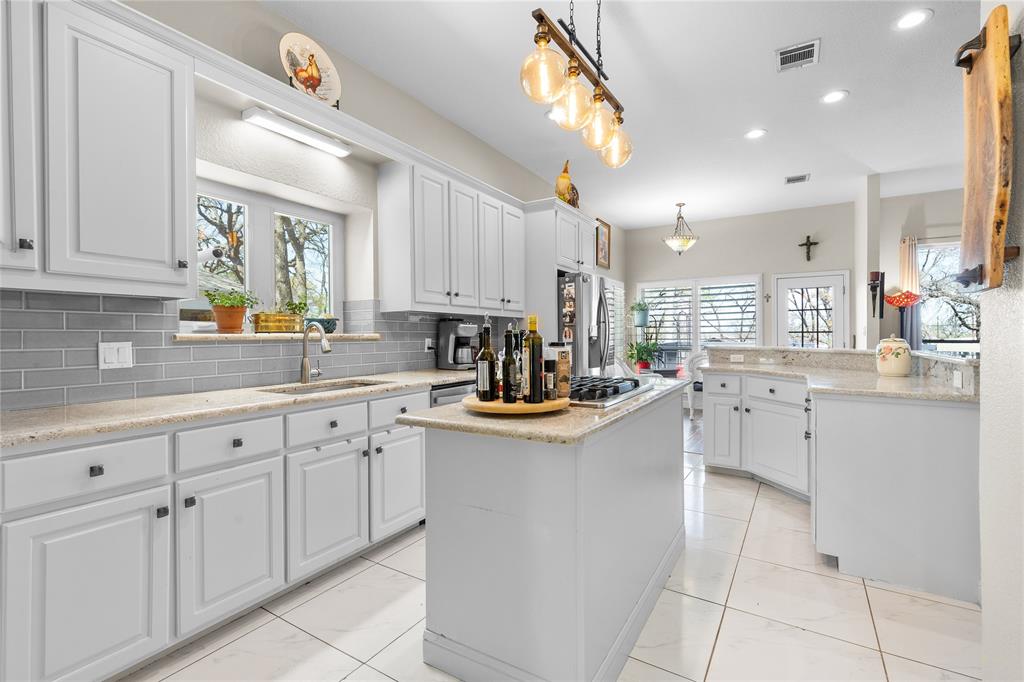 1007 Santa Fe Street Denton, TX 76205 - Photo 11 of 37 Kitchen featuring white cabinets, light stone counters, a center island, and a peninsula