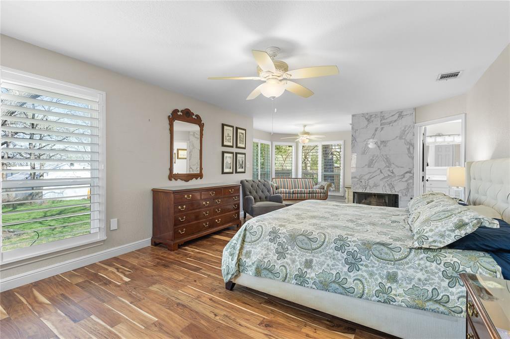 1007 Santa Fe Street Denton, TX 76205 - Photo 14 of 37 Bedroom featuring connected bathroom, dark wood-style flooring, a fireplace, and ceiling fan