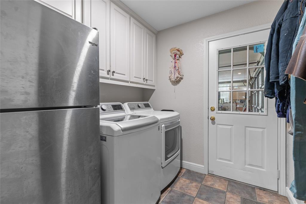 1007 Santa Fe Street Denton, TX 76205 - Photo 27 of 37 Laundry room featuring washing machine and dryer, refrigerator, stone finish floors, and a textured wall