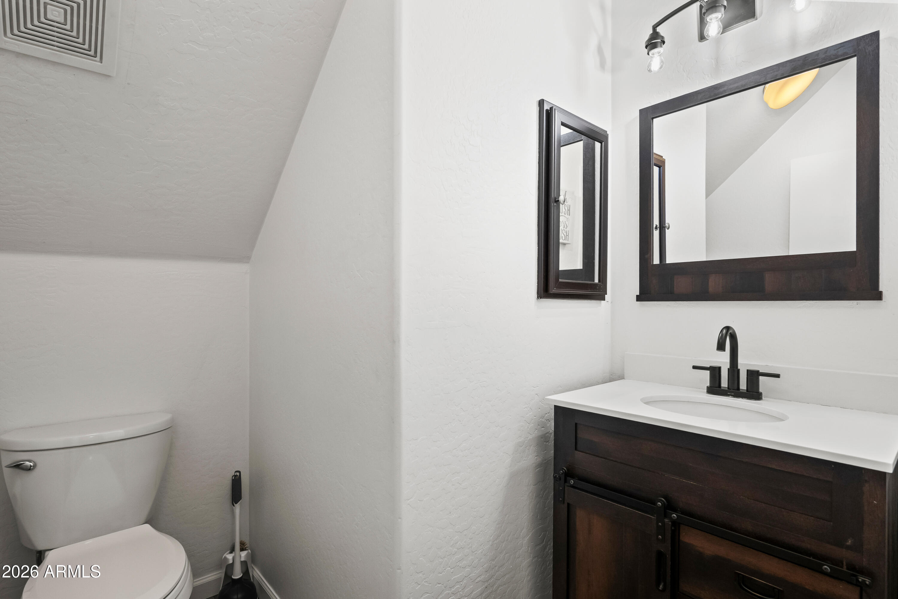 2150 East Bell Road, Unit 1159 Phoenix, AZ 85022 - Photo 12 of 26 a bathroom with a toilet a sink a mirror and a window