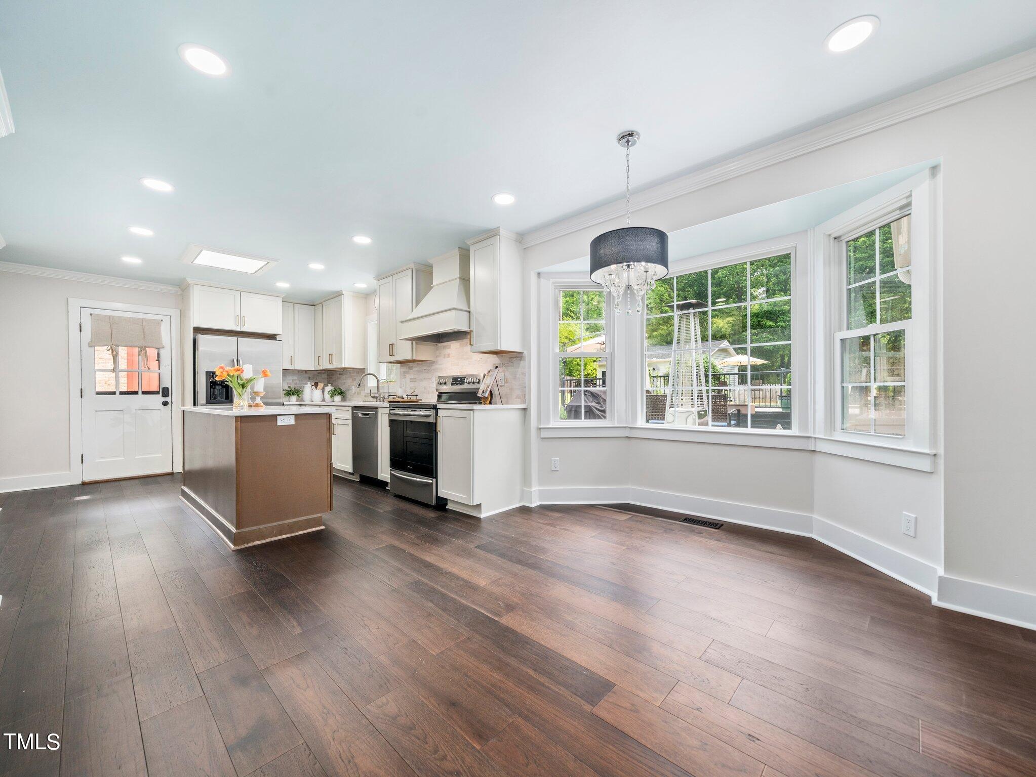 7800 Whitley Drive Raleigh, NC 27613 - Photo 4 of 17 a kitchen with stainless steel appliances wooden floors and white cabinets