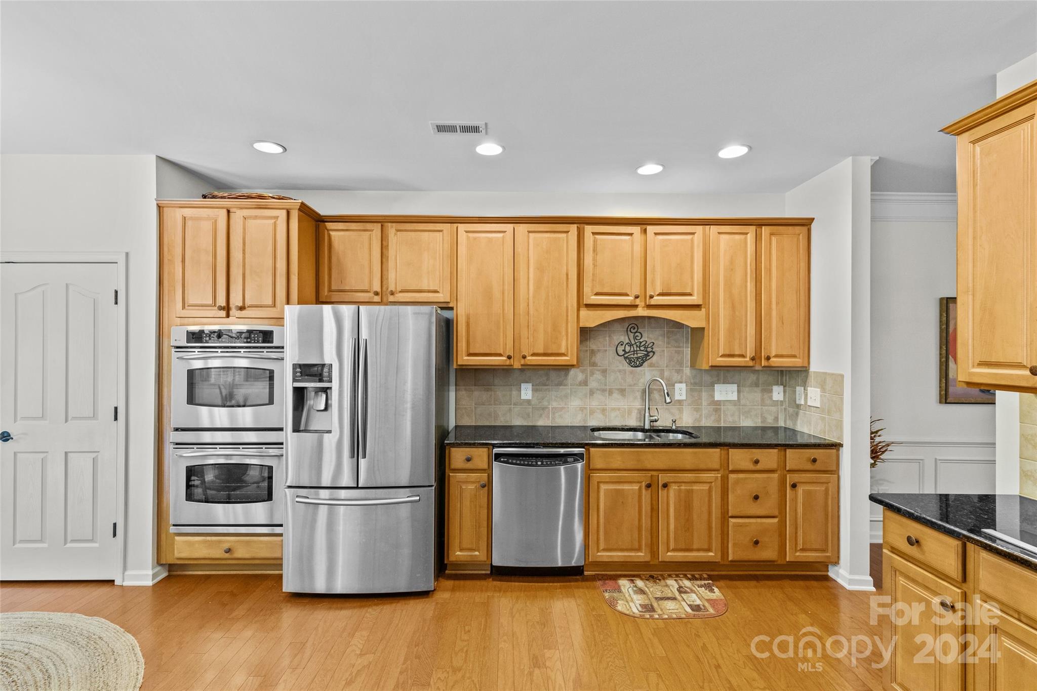 1034 Silver Gull Drive Tega Cay, SC 29708 - Photo 7 of 32 a kitchen with stainless steel appliances granite countertop a refrigerator a sink dishwasher a stove and a dining table with wooden floor